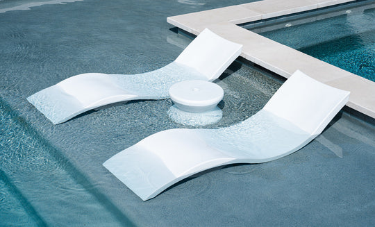 The Ledge Lounger Signature Chaise and Side Table In-Pool 6-Piece Set includes sleek white loungers and a round table, perfectly positioned in the shallow end as stylish pool ledge furniture next to a raised ledge.