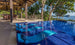 Three blue in-pool chaise loungers with matching headrest pillows on a blue tile mosaic pool ledge.