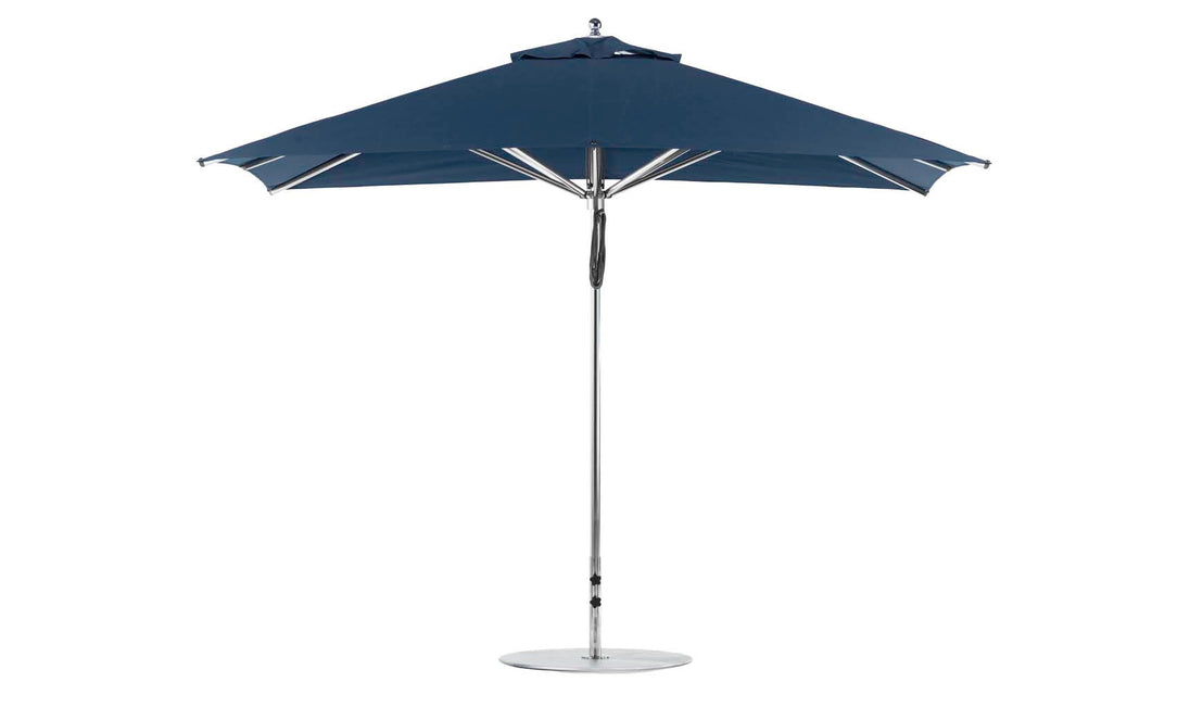 A freestanding Ledge Lounger Premier Aluminum Umbrella, 8.5 rectangle with a pulley, features a sleek metal pole, circular base, and marine-grade dark blue fabric for durability, set against a plain white background.