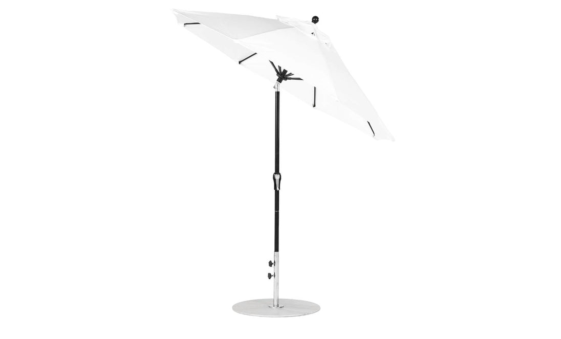 The Ledge Lounger Essential Fiberglass Umbrella - 7.5 Octagon Crank Auto Tilt features a white canopy and black pole, elegantly angled on a round base. Made with marine-grade fabrics, it offers durability and wind resistance against the white backdrop.
