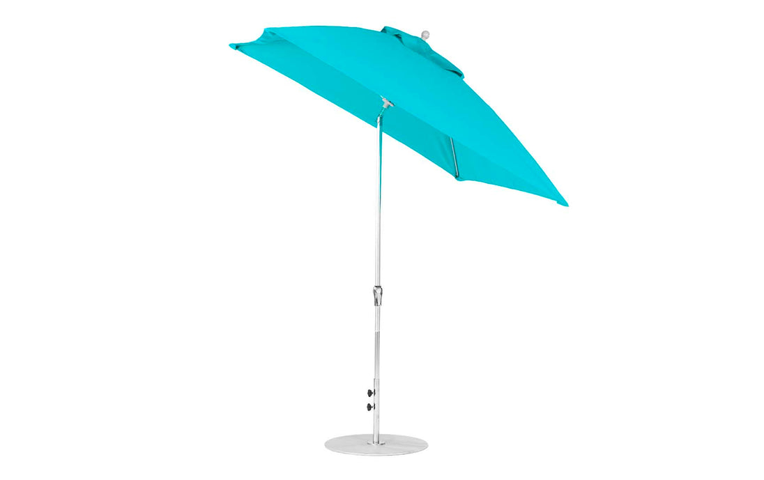 A turquoise, 7.5 square Essential Fiberglass Umbrella by Ledge Lounger features a silver, corrosion-resistant metal pole and round base. Made from marine-grade fabrics, it stands open and tilted against a plain white background.