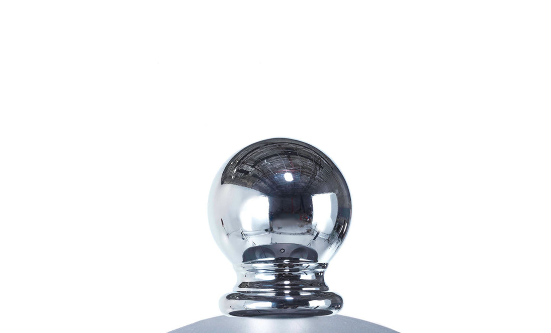 A reflective, spherical cap on the round bottle mimics the durable elegance of marine-grade fabrics found in Ledge Loungers Premier Aluminum Umbrella - 8.5 Rectangle Pulley against a white backdrop.