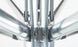 A close-up of a metallic, symmetrical structure featuring shiny silver rods and gray braided cables converging at a central hub resembles the durable framework of the Ledge Lounger Premier Aluminum Umbrella - 9 Octagon Pulley, showcasing smooth, polished surfaces and visible fasteners.