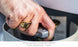A hand wearing a gold ring turns a valve in the concealed compartment of a propane tank. Captioned, Halo Aglow Bundle by Ledge Lounger.