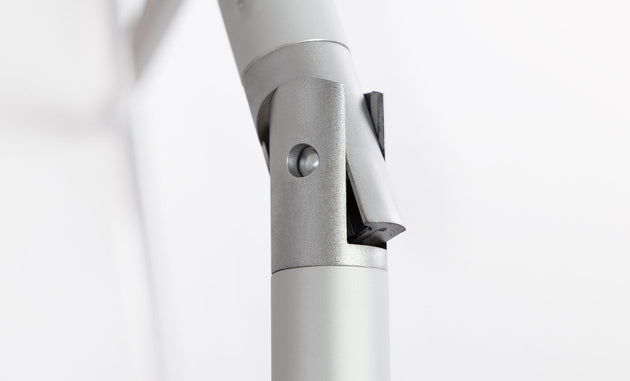 Close-up of a silver-gray metallic hinge with cylindrical components and a pivot mechanism, designed for the 7.5 Octagon Signature 360° Tilt Umbrella by Ledge Lounger, set against a plain white background.